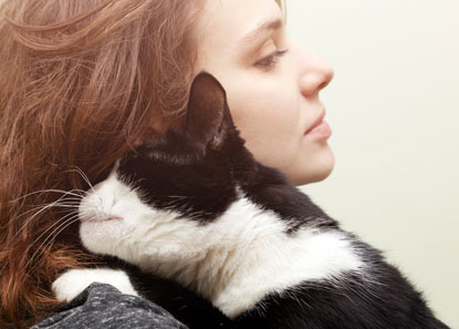 woman with red hair cuddling black and whit cat