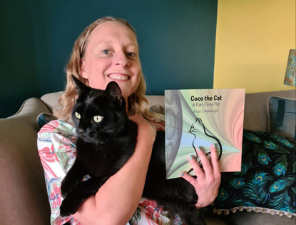 blonde woman holding black cat and Coco the Cat book