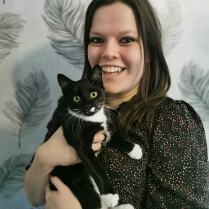 brunette woman holding black-and-white kitten