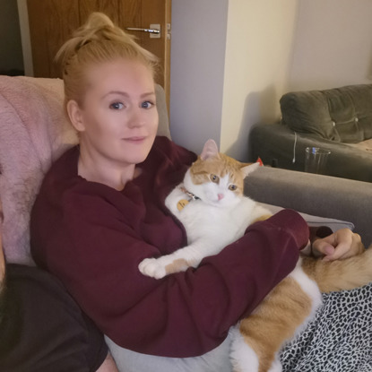 blonde woman sitting with ginger and white cat on her lap