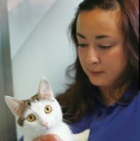 brunette woman holding white and tabby cat