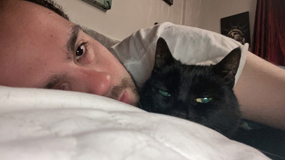 man and black cat laying in bed