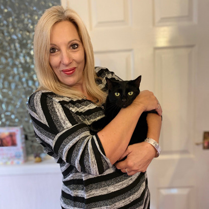 blonde woman in stripy top holding lucky black cat