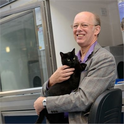 man in grey suit holding black cat in cat rehoming centre