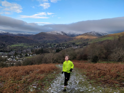 young boy in yellow jacket running on a mountain path