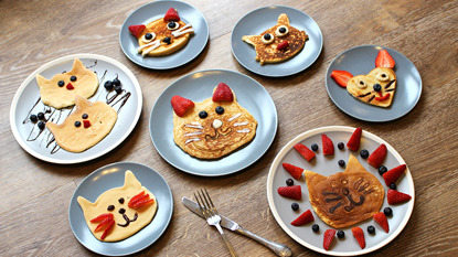 A selection of pancakes decorated to look like cat faces on a table