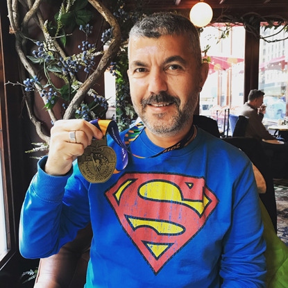 man wearing superman jumper and holding marathon medal