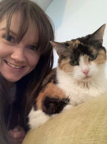 brunette woman next to tortoiseshell-and-white cat