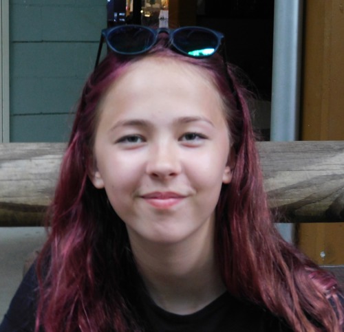 young girl with long purple hair and sunglasses on her head