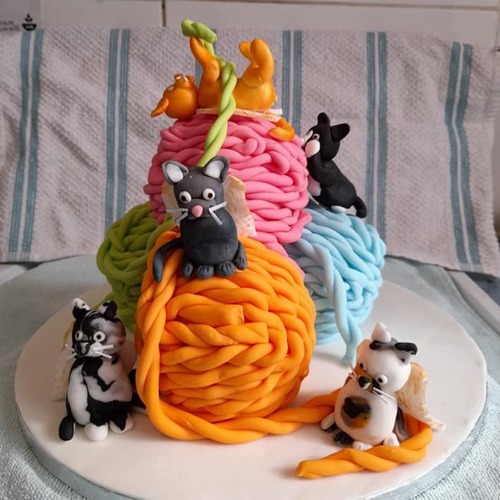 cake decorated to look like colourful balls of wool with cats playing on them
