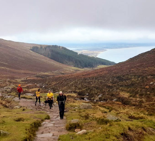 Group of four people walking up a mountain path