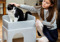 A young person stroking a black-and-white cat sat in a grey plastic cat bed.