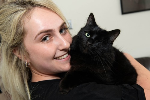 long-haired blonde woman holding black one-eyed cat