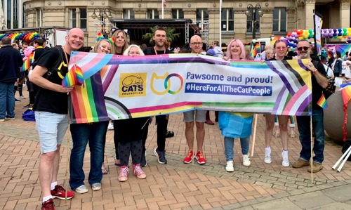 Group of people holding up banner with Cats Protection logo and text saying 'Pawsome and proud! #HereForAllTheCatPeople'