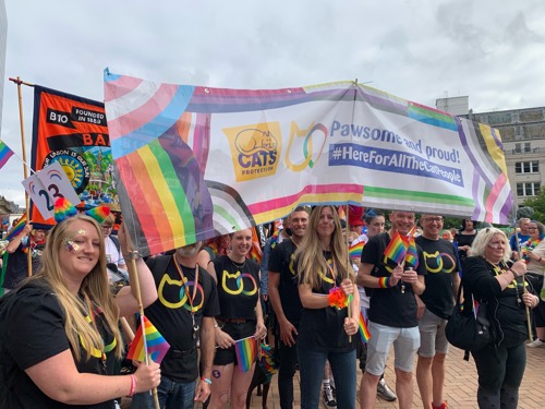 Group of people holding banner with Cats Protection logo and text saying 'Pawsome and proud! #HereForAllTheCatPeople'