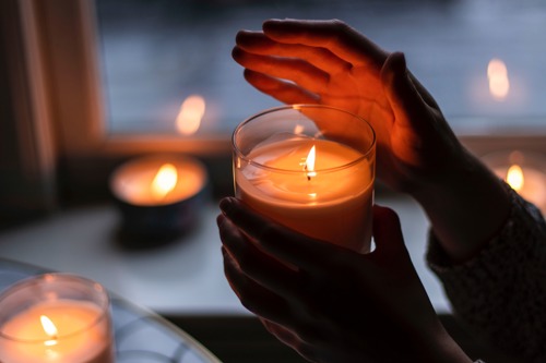 Human hands holding a lit candle