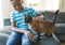 Boy sat on sofa stroking brown cat next to him