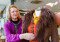 A person adjusting a brown coat on a mannequin in a shop.