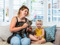 Person holding a brown tabby cat while sitting beside a child on a sofa.