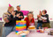 A woman blowing out candles on a 60th birthday cat while four other people stand around her clapping