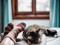 A tabby-and-white cat asleep on a bed next to a pair of human feet wearing colourful fluffy socks